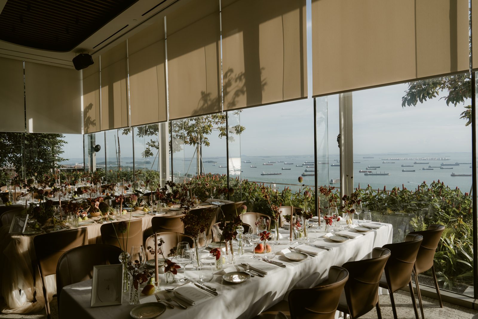 Indoor wedding reception at 1-Alfaro Singapore with long banquet tables and floor to ceiling sea view windows