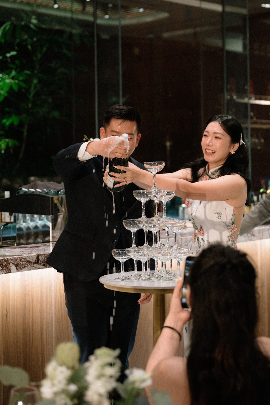 Bride and groom pouring a champagne tower at their 1-Alfaro wedding reception in Singapore